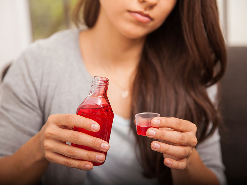 Teen pouring cough syrup