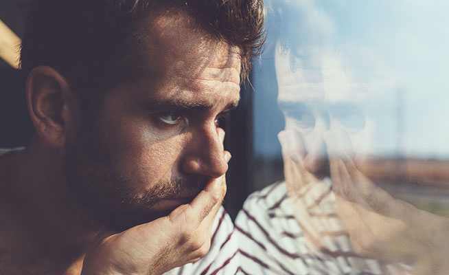 Depressed man looking out of a window