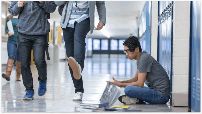 High school boy picking up books after being bullied