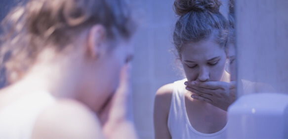Young girl with eating disorder covering her mouth after getting sick