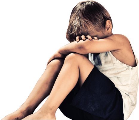 Boy cradling his legs at the bottom of a set of stairs.