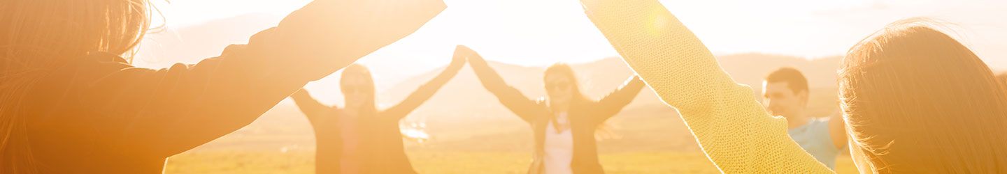 group of friends outdoors with their arms in the air and holding hands