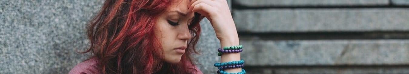 Girl holding her head in her hands on the street