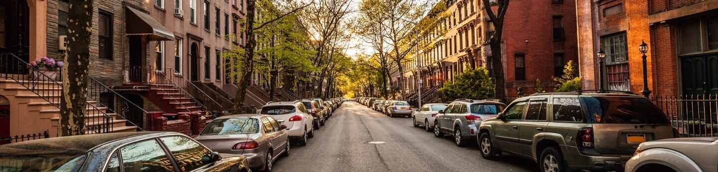 Residential street with cars parked along the buildings