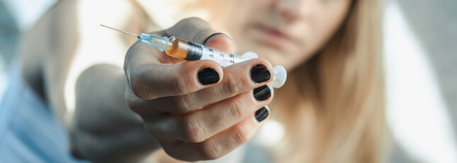 Woman holding needle with drugs