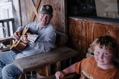 Lee McCormick, a recovering addict, sitting on his porch with a guitar