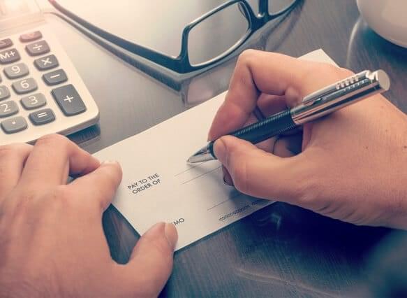 Person writing out a check on their desk