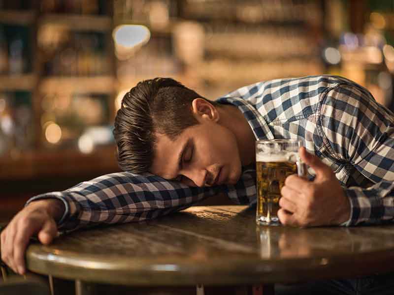 Young drunk man sleeping on the table in a bar