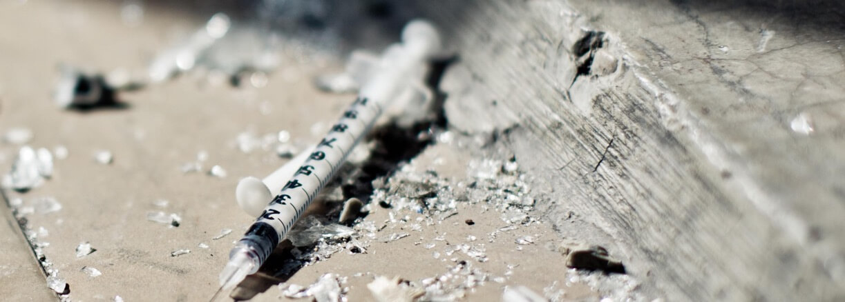 syringe among glass shards