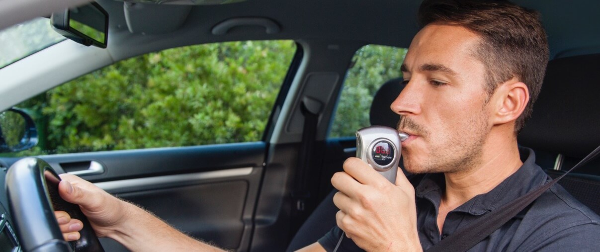 man blowing into an ignition interlock device