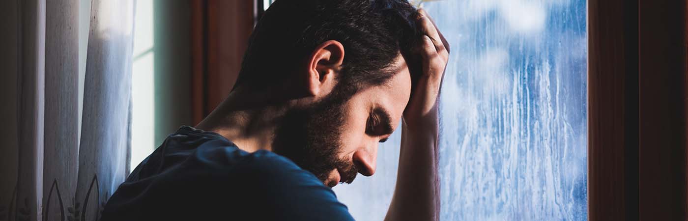 Sad man sits against the window
