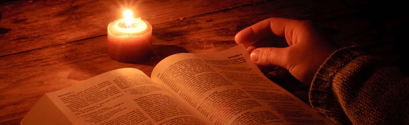 Reading from the Bible at candle light.