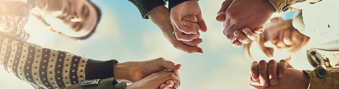 Group of people holding hands and praying to together in a circle
