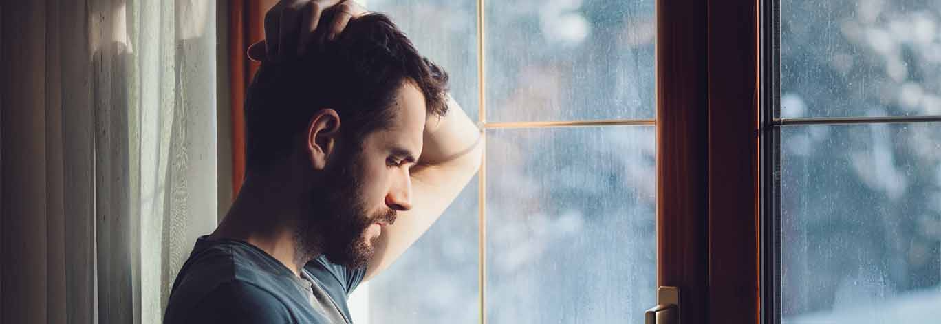 Depressed man stares out the window